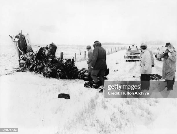 Group of men view of the wreckage of a Beechcraft Bonanza airplane in a snowy field outside of Clear Lake, Iowa, early February 1959. The crash, on...