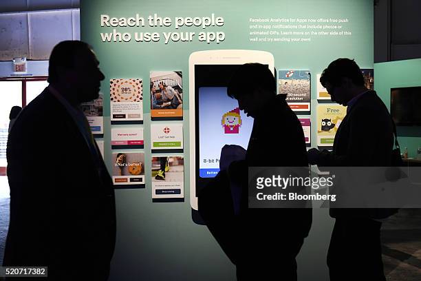 The silhouettes of attendees are seen walking past a booth during the Facebook F8 Developers Conference in San Francisco, California, U.S., on...