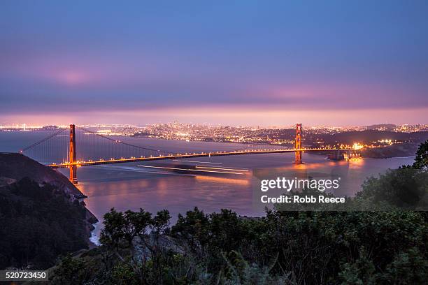 the golden gate bridge, san francisco skyline and san francisco bay in evening - bucht-von-san-francisco stock-fotos und bilder