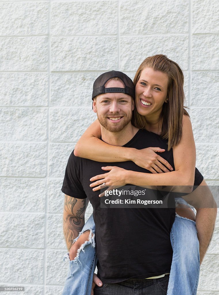 Young, hip couple against a white wall