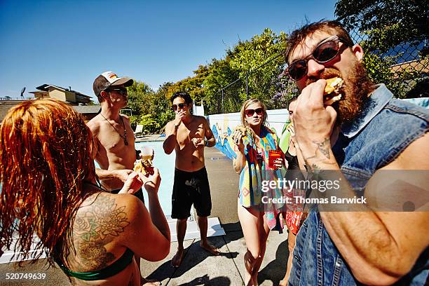 friends eating hamburgers during pool party - adults eating hamburgers foto e immagini stock