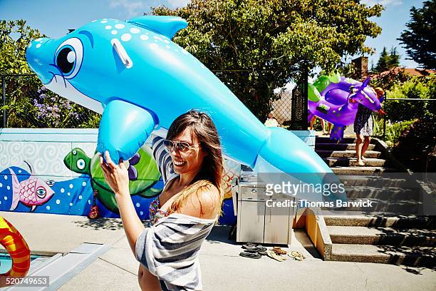 smiling woman carrying large inflatable pool toy - celebrates firsts imagens e fotografias de stock