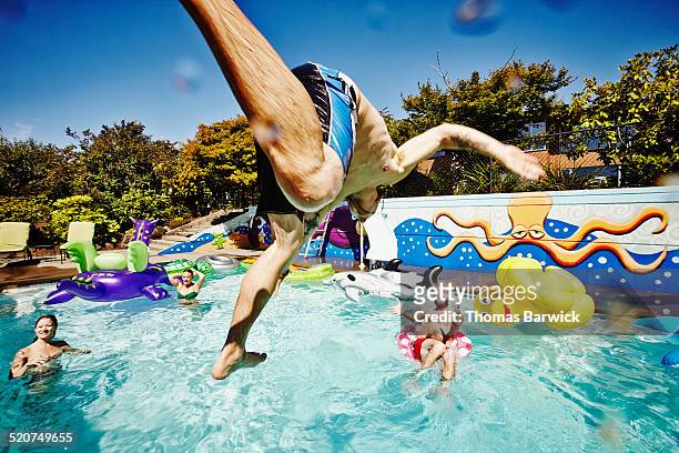 man in mid air jumping into pool during party - friends prank stock pictures, royalty-free photos & images