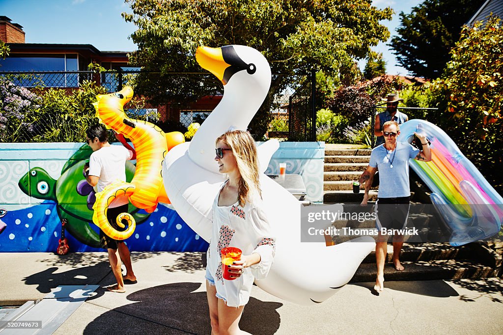 Friends carrying drinks and inflatable pool toys