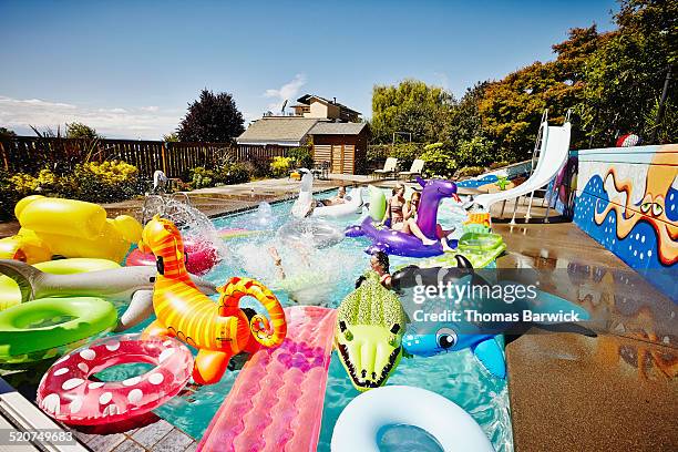 friends having a pool party with inflatable toys - fiesta de piscina fotografías e imágenes de stock