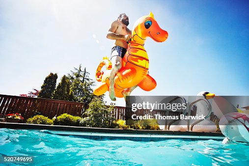 Man jumping into pool with inflatable pool toy Man jumping into pool with inflatable pool toy