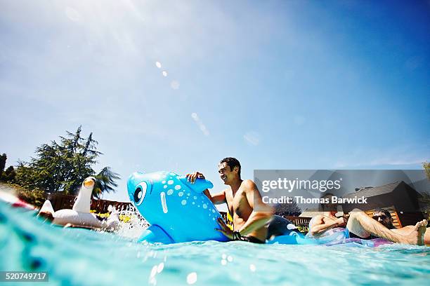 smiling man on inflatable toy in outdoor pool - blue sky friends stock pictures, royalty-free photos & images
