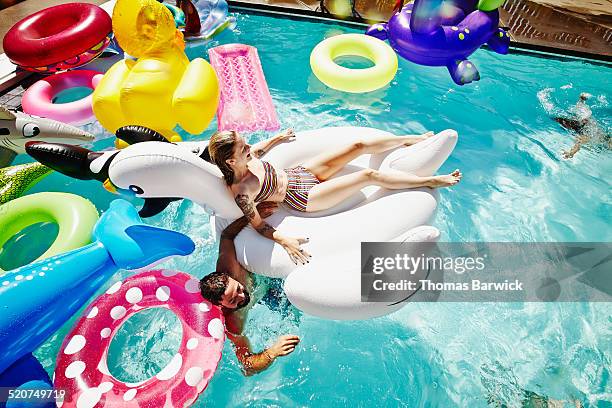 woman floating on inflatable pool toy during party - aufblasbarer gegenstand stock-fotos und bilder