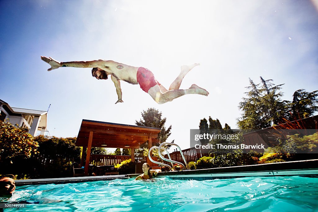 Man in mid air diving into outdoor pool