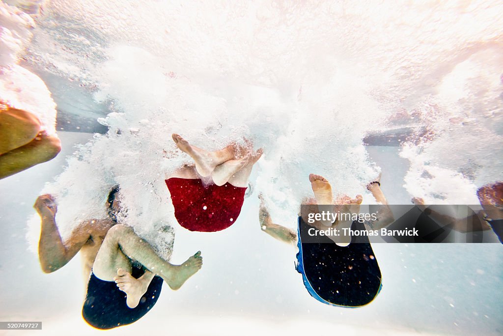 Friends jumping into pool together underwater view