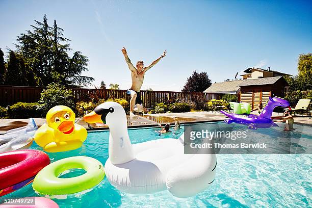 man with jumping into pool during party - inflatable pool toys imagens e fotografias de stock