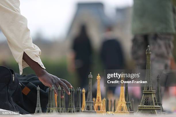 man selling statuettes of the eiffel tower in the tuillerie gardens, paris - frankreich souvenir reise stock-fotos und bilder