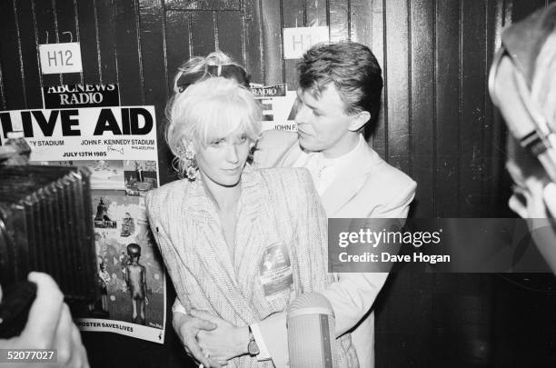 English rock star David Bowie backstage with TV presenter and wife of Bob Geldof, Paula Yates at the Live Aid concert at Wembley Stadium, London,...