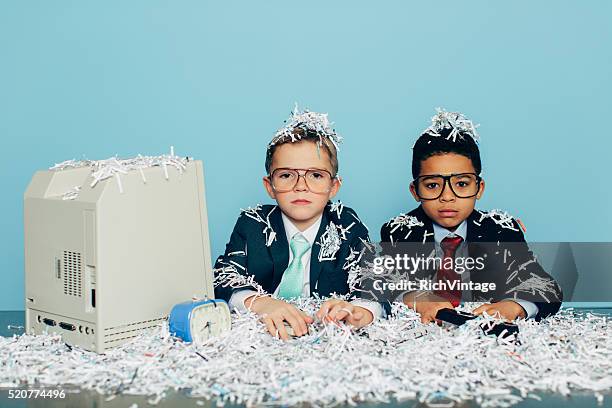 young businessmen covered in shredded paper at office desk - shredded paper stock pictures, royalty-free photos & images