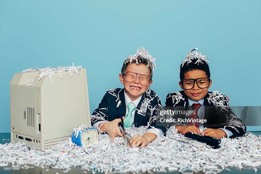 Young Businessmen Covered in Shredded Paper at Office Desk