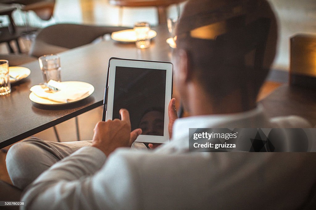 Rear view of a young handsome businessman holding tablet