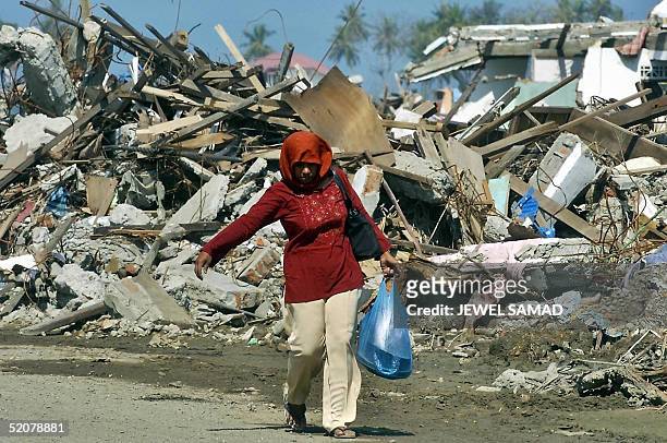 An Acehnese tsunami surviving woman walks past debris of houses in Banda Aceh, 29 January 2005. Peace negotiators for the Indonesian government and...