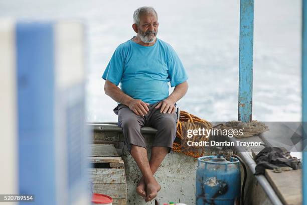 Year old Abu Issam, a fisherman of 50 years sits at the back of the boat as his crew prepare for a fishing trip of the coast od Gaza on April 9, 2016...