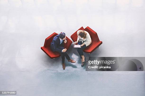 overhead view of two business persons in the lobby - business meeting stockfoto's en -beelden