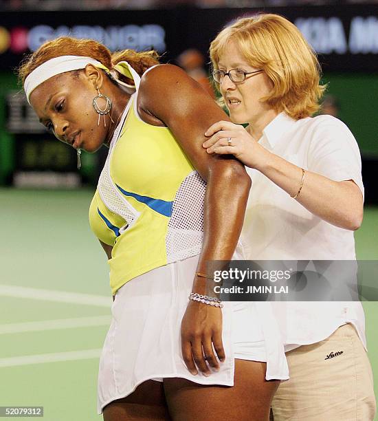 Trainer works on Serena Williams of the US during an injury time-out while playing against compatriot Lindsay Davenport in the women's singles final...