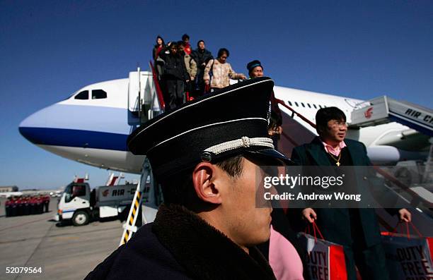 Passengers disembark the first direct flight from Taipei to Beijing by Taiwan's China Airlines as a policeman looks on January 29, 2005 at Beijing's...