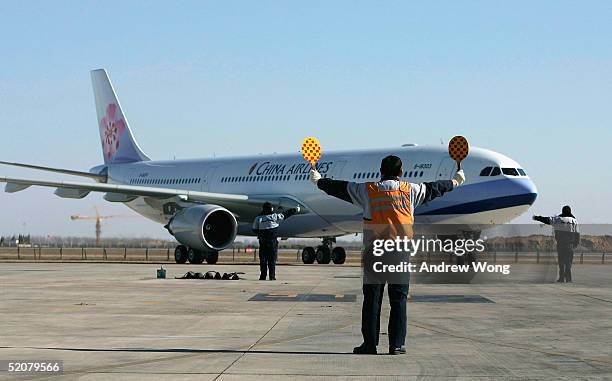 Chinese ground crew members direct the first direct flight from Taipei to Beijing by Taiwan's China Airlines on January 29, 2005 at Beijing's Capital...
