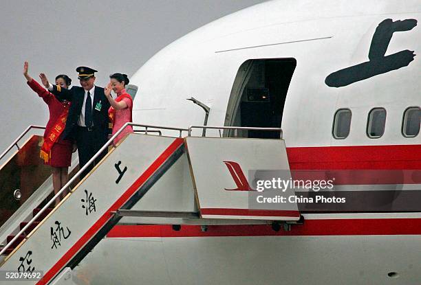 Crew members wave during a ceremony to mark the departure of Shanghai Airlines' first direct flight from Shanghai to Taiwan, at the Pudong...