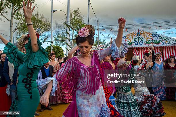 Women wearing traditional Sevillana dresses dance a Sevillana at the Feria de Abril on April 12, 2016 in Seville, Spain. The Feria de Abril has a...