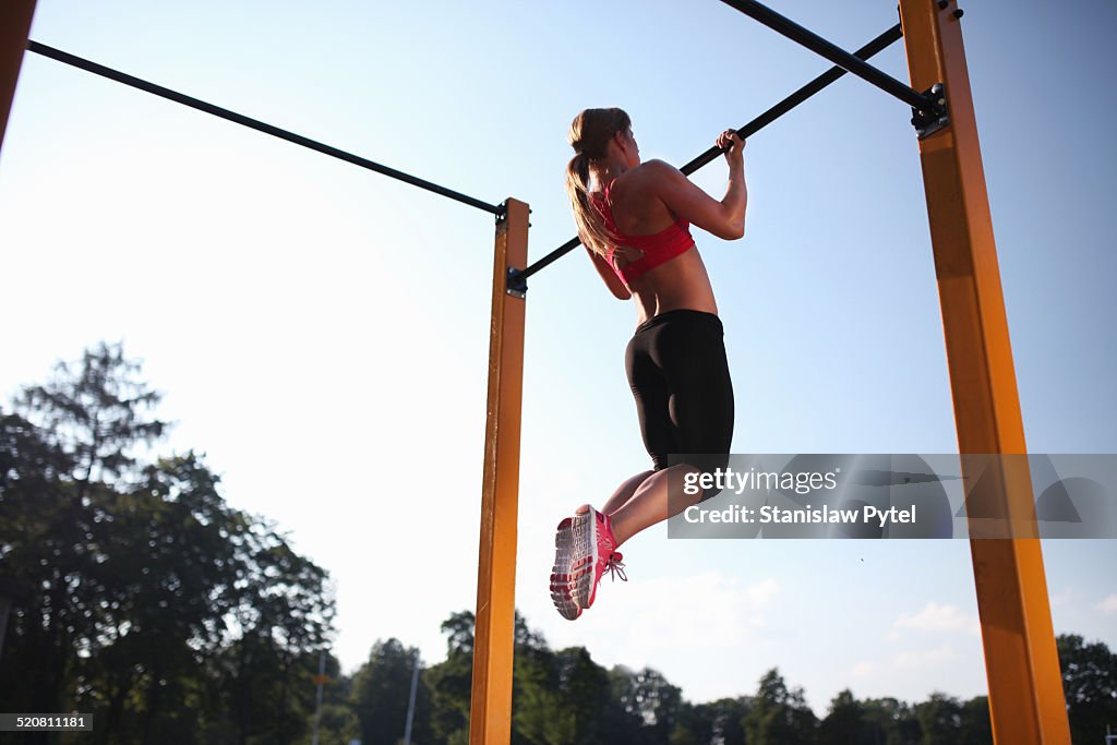 Girl training on chin-up bar outdoor