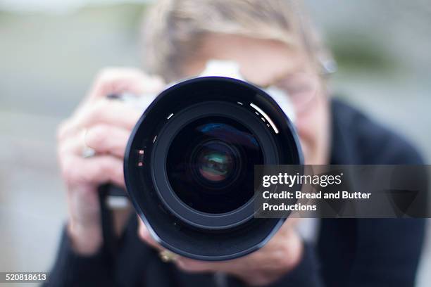 mature adult woman photographing - カメラ　レンズ ストックフォトと画像