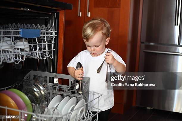 little boy with cutlery near the dishwasher - child proofing stock pictures, royalty-free photos & images