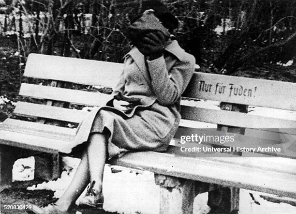 Jewish female hides her face from people as she sits on a Jew only bench. Anti semitic segregation was implemented in Germany when the Nazi party...