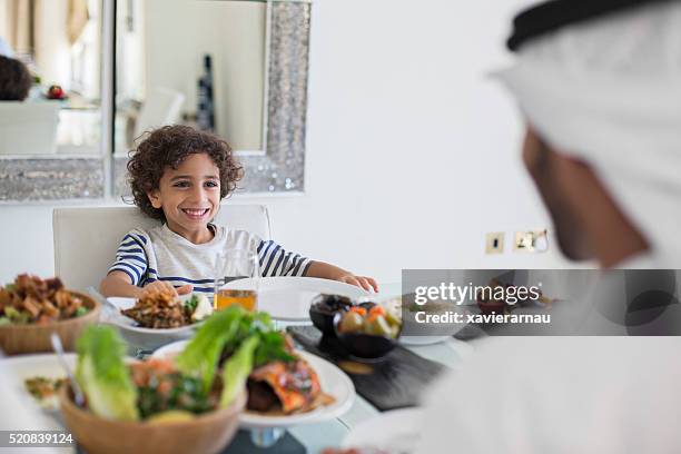 middle eastern father talking with his son while eating - dubai cares stock pictures, royalty-free photos & images