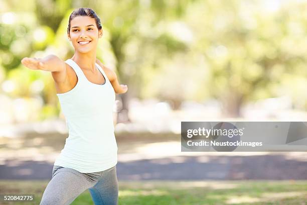 smiling woman practicing yoga in warrior 2 pose - warrior position stock pictures, royalty-free photos & images