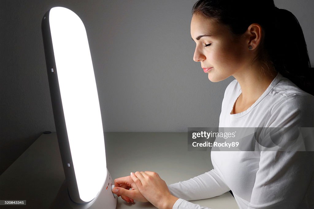 Young woman administering a light therapy agains winter depression