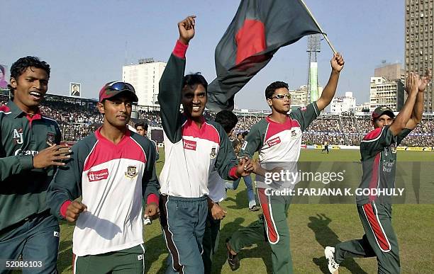 Bangladeshi cricketers run with national flag as they celebrate their victory in the fifth and final one day international cricket match between...