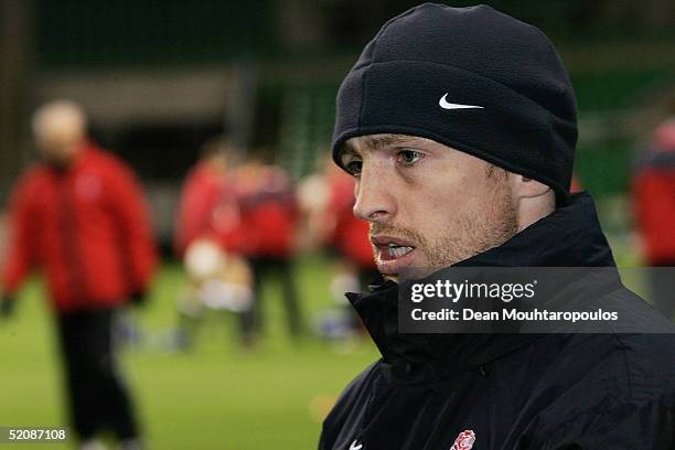 Matt Dawson talks to staff on the sidelines while the England Rugby Union training session continues in the background at Twickenham Stadium on...