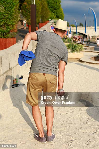 a man playing boules, (bocci, petanque) on paris plage, the summer beach on the banks of the seine, - bocce ball stock pictures, royalty-free photos & images