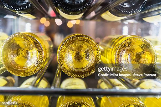 view of bottles of white wine laid down on a rack in a cellar. - flaschenpost stock-fotos und bilder