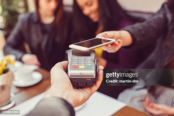 woman making contactless payment with smartphone - wallet stockfoto's en -beelden