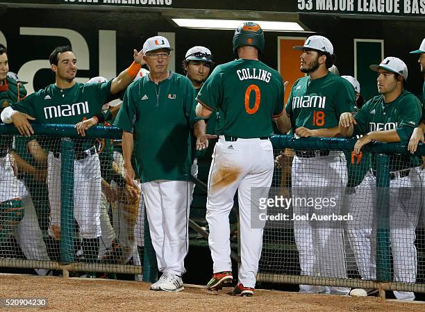 Zack Collins is congratulated by head coach Jim Morris of the Miami Hurricanes after scoring on a wild pitch by the Nova Southeastern Sharks in the...