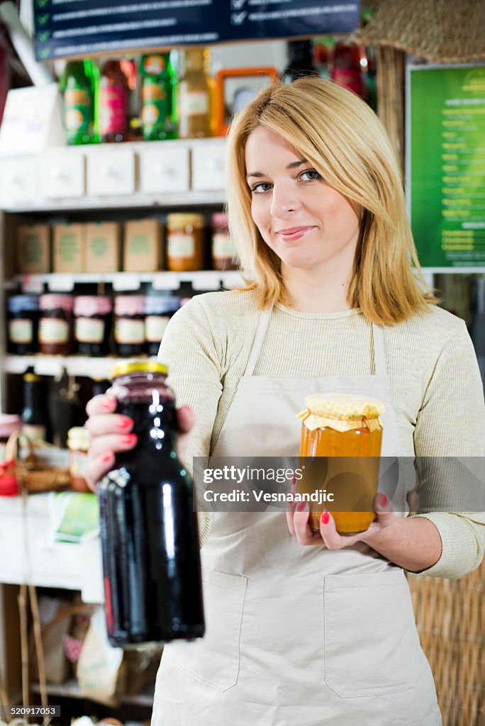 Joven mujer sosteniendo contratuerca caseras y jugo en la tienda