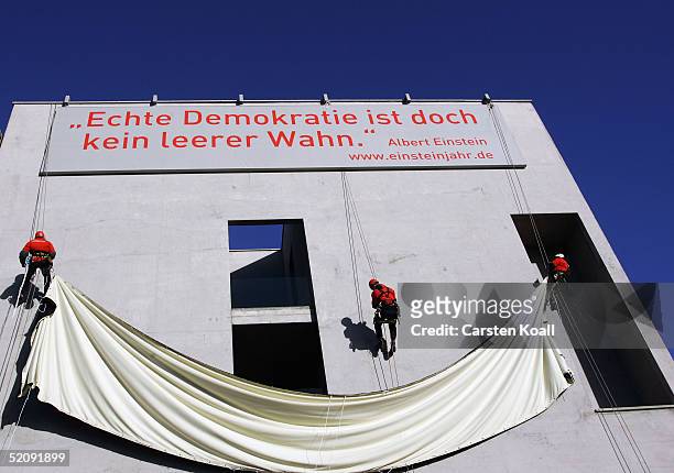 Abseilers unveil a banner carrying the Albert Einstein quote "...genuine democracy is nevertheless no empty illusion" on the external wall of the...