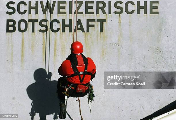 An abseiler is seen under a sign reading "Swiss Embassy" after unveiling a banner carrying the Albert Einstein quote "...genuine democracy is...