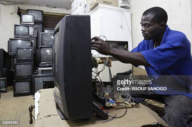 Man repairs a used television set 01 February 2005 at a second-hand market, called "France aurevoir" , in the poor neighborhood of Adjame in Abidjan....