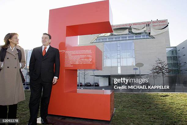 German Chancellor Gerhard Schroeder and Education Minister Edelgard Bulmahn stand in front of a giant E as workers in the background unveil banners...