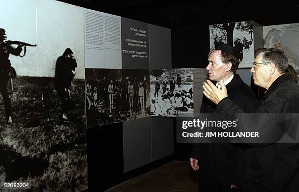 German President Horst Koehler looks at a mural photo showing a Nazi soldier aiming a rifle at a Jewish woman as a guide talks during a tour of the...