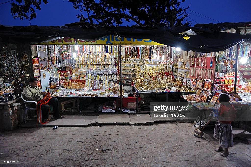 Krämer sitzen neben seiner Shop bei Nacht Markt in Orachha