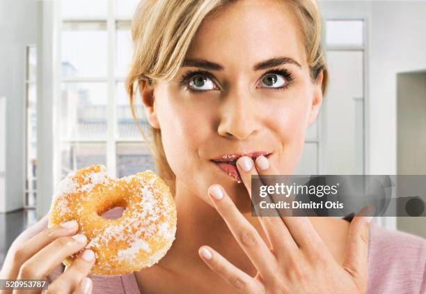 blonde woman eating a sugar coated doughnut - sugar stock pictures, royalty-free photos & images