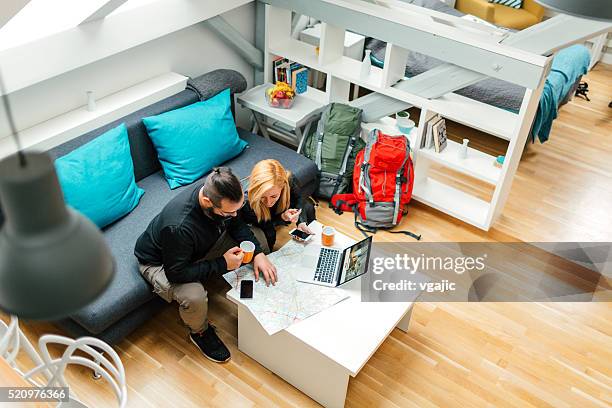 backpackers looking at map in their rented apartment. - backpacker apartment stock pictures, royalty-free photos & images